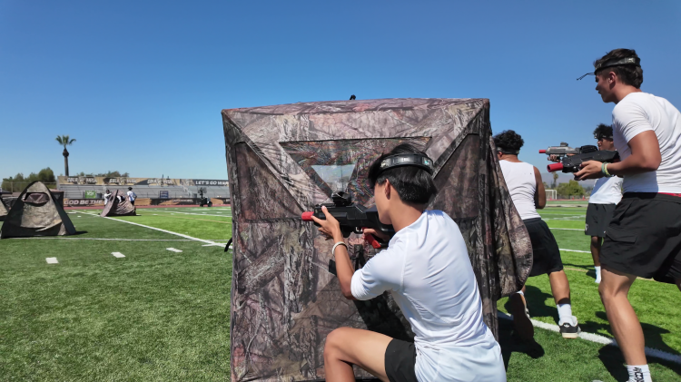2 people using a camo tent as cover while playing laser tag